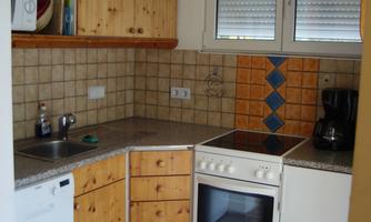 A modern kitchen with wooden cabinets and a stove. The kitchen furnishings are bright and functional.