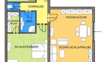 Floor plan of a lakeside house with two bedrooms, a bathroom, and a living area with kitchen. Outside, there is a terrace with dining area.