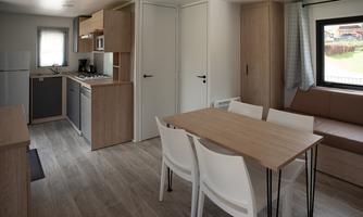 A modern kitchen with wooden cabinets and a dining table in a bright room. The room is inviting and well-furnished.