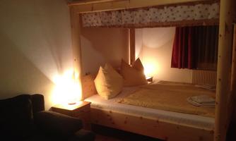 A cozy bedroom with a double bed and large pillows. The warm lighting creates an inviting atmosphere.