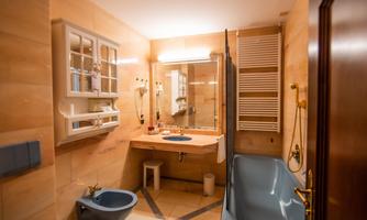 A modern bathroom with a bright stone floor and comfortable amenities. There is a bathtub, a sink, and a large mirror.