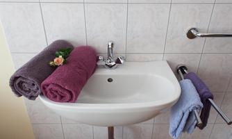 An elegant sink with two towels in different colors. A small flower lies on one of the towels.