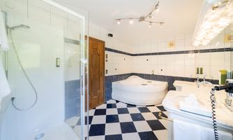A modern bathroom with a shower area and a large bathtub. The floor is designed in a checkerboard pattern in black and white.