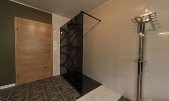 A modern bathroom with a glass shower and elegant tiles. The walls are in neutral colors and the door is made of wood.