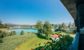 A picturesque landscape with a peaceful lake and lush greenery. The flowers on the balcony add a colorful accent.