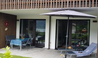 A cozy outdoor area with a table and chairs, surrounded by green plants. An umbrella provides shade for relaxing hours outdoors.