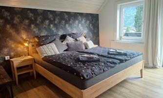 A cozy bedroom with a large bed and modern decorations. The room has plenty of natural light and a view outside.
