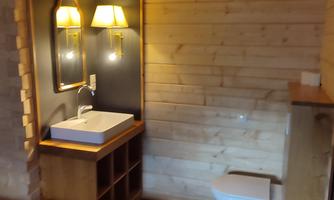 A modern bathroom with wooden cladding and a sink. The walls are made of wood, and there is soft lighting.