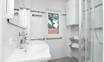 A modern bathroom with a shower and a sink. It is bright and designed in a minimalist style.
