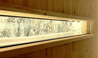 A window with a view of snow-covered trees. The wooden frame gives the image a warm touch.