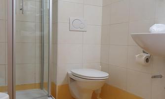 A modern bathroom with a shower, sink, and toilet. The walls are kept in light colors.