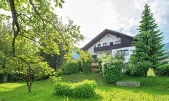 A beautiful house surrounded by green grass and trees. The scenery looks inviting and peaceful.