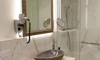 A modern bathroom with an elegant shower and a gray sink. The room has bright walls and a stylish mirror frame.