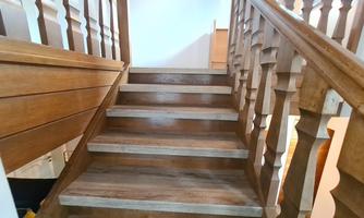 A wooden staircase leads up, surrounded by a bright room. The steps are clearly visible and appear inviting.