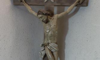 A wooden cross with a depiction of the crucifixion of Jesus Christ. The scenes are designed simply and traditionally.