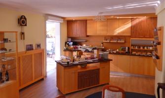 A cozy dining room with a buffet filled with various foods and drinks. Bright wooden furniture and plenty of natural light create an inviting atmosphere.