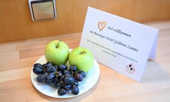 A welcome sign and a plate with fresh apples and grapes. The sign welcomes guests at the Boutique Hotel Goldenes Lamm.