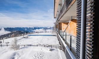 A modern building in a snowy landscape. In the background, mountains and a clear sky are visible.