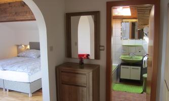 A cozy bedroom with a double bed and a modern bathroom. The entrance area is bright and inviting.