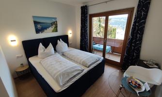 A cozy bedroom with two beds and a balcony. There is a small table with fresh fruit and a beautiful view.