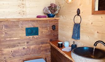 A modern bathroom with wood paneling and an elegant stone sink. The atmosphere is warm and inviting, with natural materials and minimalist design.