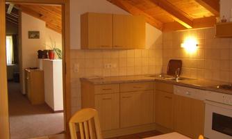 A cozy kitchen with wooden shelves and a modern stove. The room has an open design and offers a view of the adjoining living area.