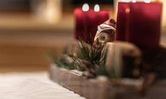 A festively decorated table with red candles and fir branches. The arrangement radiates a cozy, Christmas atmosphere.