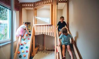 A play area with a climbing wall and slides. Children play and climb happily in a bright room.