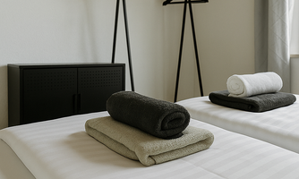 A modern bedroom with two beds. There are towels on the beds and a coat rack on the wall.