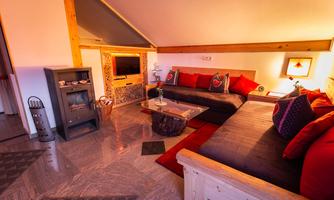 A cozy living room with comfortable sofas and colorful cushions. It has a warm atmosphere with wooden details and soft lighting.