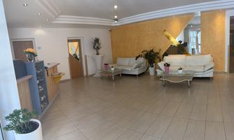 A bright reception area with modern furniture and plants. The walls are designed in warm shades, creating an inviting atmosphere.