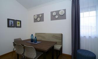 A modern dining area with a wooden table and elegant chairs. Decorative elements and pictures are attached to the wall.