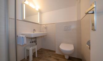 A modern bathroom with a bright decor. There is a sink, a toilet, and a mirror.
