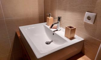 A modern sink with an elegant faucet. Next to the basin are two wooden containers for storage.