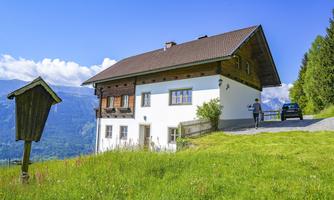 A beautiful house in a hilly landscape. The surroundings are green and sunny, with a clear blue sky.
