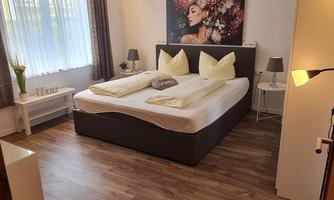 A modern bedroom with a large bed and beautiful wall art. The room is bright and inviting, with wooden floors and soft colors.