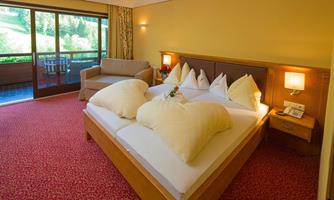 A cozy bedroom with a large bed and comfortable pillows. The room has a beautiful view of the terrace and nature.