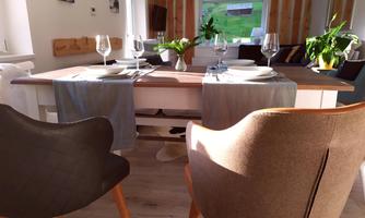 A modernly furnished dining area with a table that is beautifully set. Two chairs are at the front, creating an inviting atmosphere.