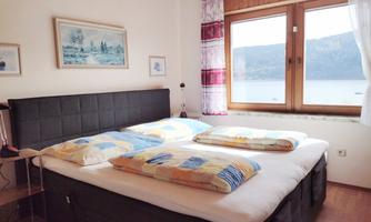 A cozy bedroom with a large bed and colorful blankets. Large windows provide a view of the countryside.