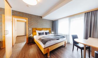 A modern hotel room with a large bed and a table.  
Large windows let in plenty of light and create a pleasant atmosphere.