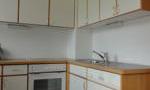 A modern kitchen with white cabinets and wooden details. The equipment includes a stove, an oven, and a sink.