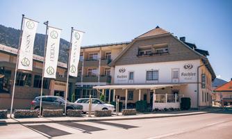 A modern hotel with striking flags and a clear, sunny sky. The facade is welcoming and well-maintained, perfect for guests.