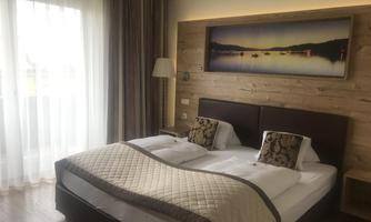 A cozy hotel room with a large bed and modern furniture. The window lets in plenty of daylight.