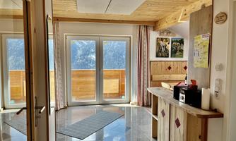 A bright, modern room with wooden elements and large windows. The windows offer a view of the mountains.