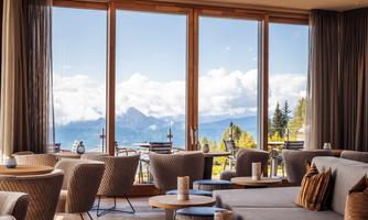A modern café with panoramic windows and a view of the mountains. Cozy furniture and a bright, inviting atmosphere.