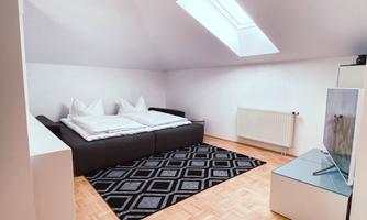 A cozy bedroom with a double bed and a television. Large windows allow for plenty of daylight.