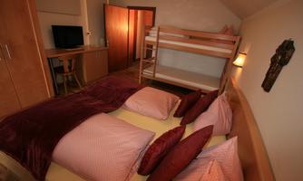 A cozy room with a double bed and bunk bed. There is a television and a desk in a bright, inviting space.