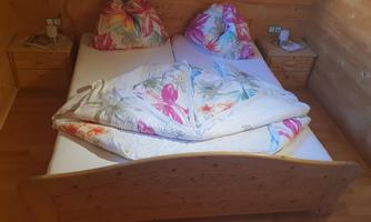 A cozy bedroom with a large double bed and colorful pillows. Next to the bed are two nightstands with lamps.