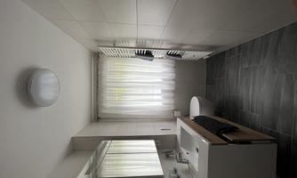 A modern bathroom with a sink and a large mirror. It has light walls, gray tiles, and a window with curtains.