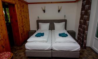A cozy bedroom with two separate beds and blue towels. The walls are made of wood and there are decorative elements like antlers.